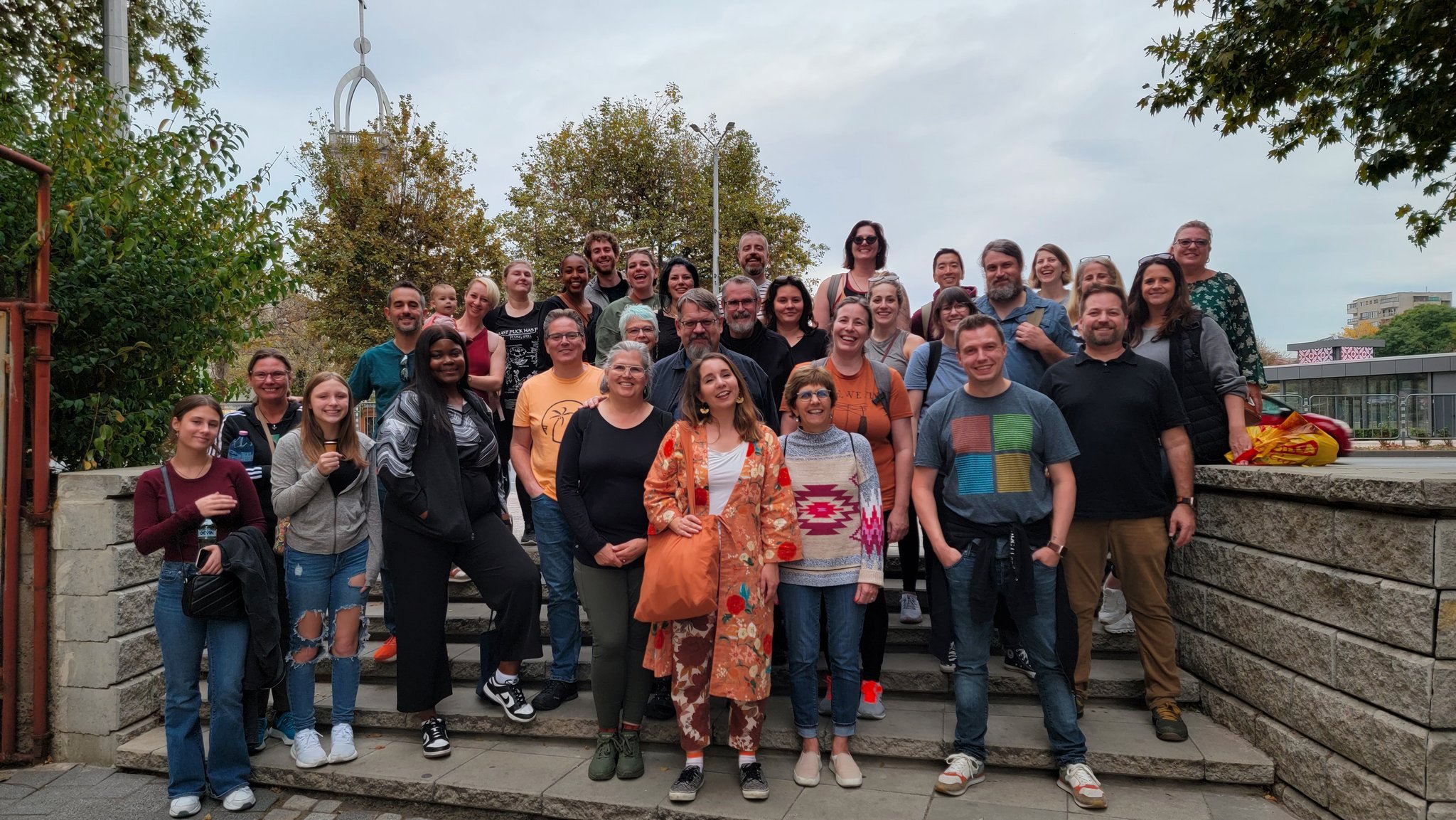 A group of people smiling for a photo in a city with trees in the background.